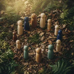 Représentation symbolique d’une constellation familiale avec figurines en bois disposées en cercle sur un sol forestier