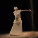 Danseur de butô de la compagnie Sankai Juku, le corps recouvert de blanc, dans une posture lente et expressive sur scène.